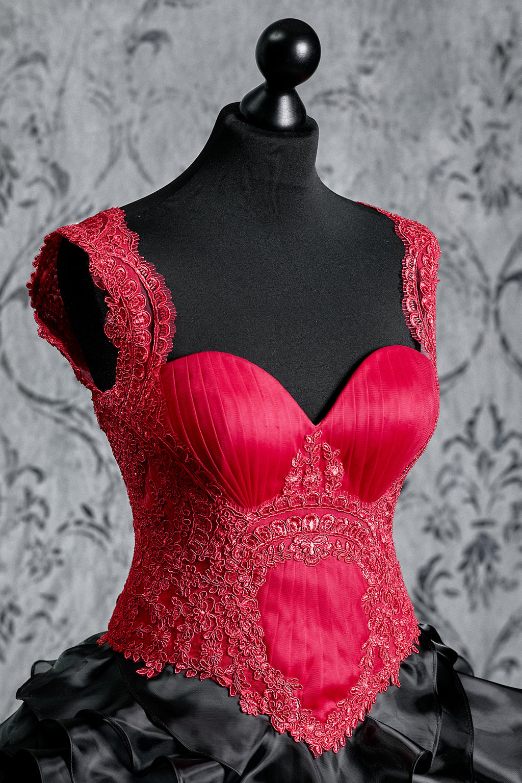 Bright red corset bodice with intricate embroidery and lace details, contrasted by a voluminous black skirt inspired by gothic fashion