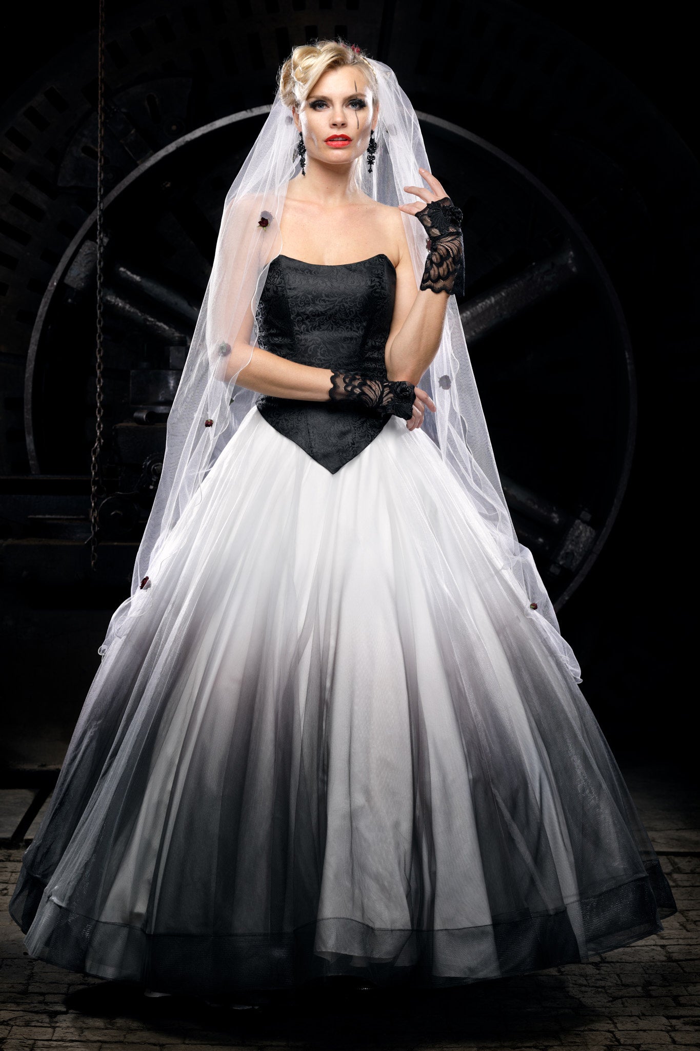 Woman wearing a black and white Victorian wedding dress with a black corset bodice, flowing tulle skirt and long bridal veil, styled as an alternative bride