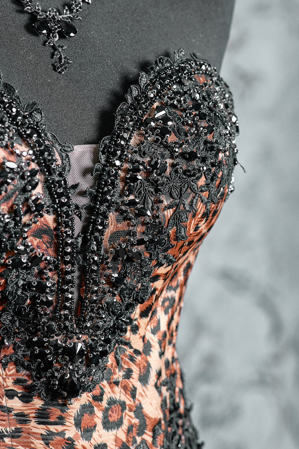 Ornate black corset bodice with intricate embellishments and leopard pattern details, paired with a voluminous ruffle skirt in close up
