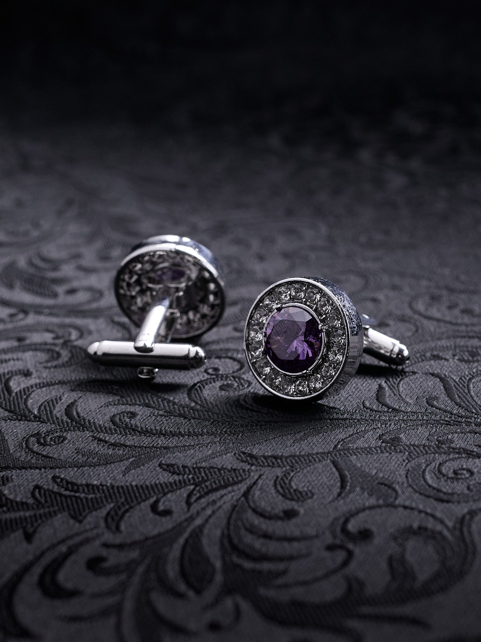 Imperial Violet cufflinks featuring a large central purple crystal surrounded by a halo of small white stones on a dark background.