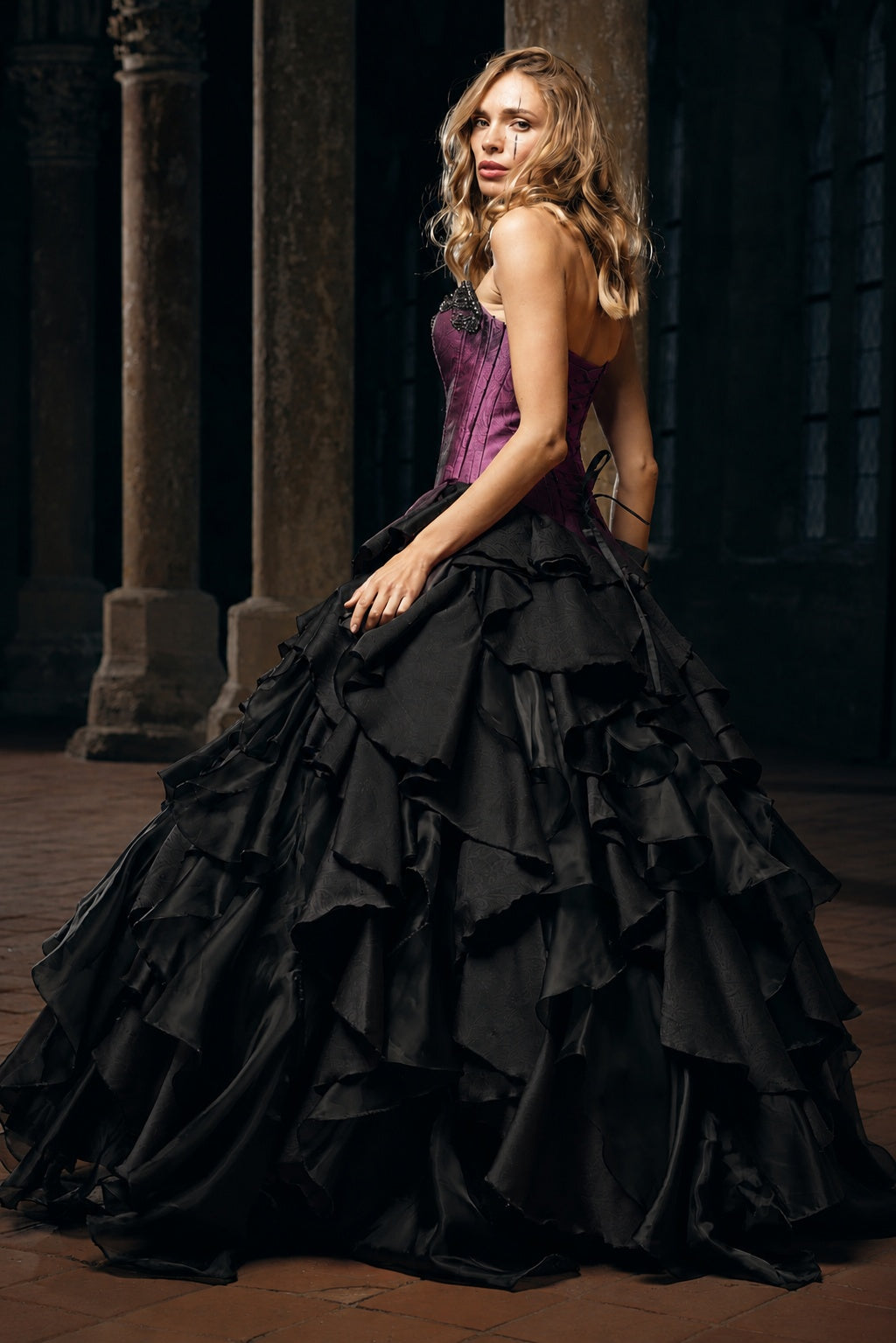 Woman wearing a purple corset gown with dramatic black ruffle skirt, Victorian dress inspired alternative bride aesthetic in a gothic setting