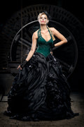 Woman wearing an emerald green corset gown with a dramatic black skirt, Victorian dress inspired alternative bride look in a steam punk setting