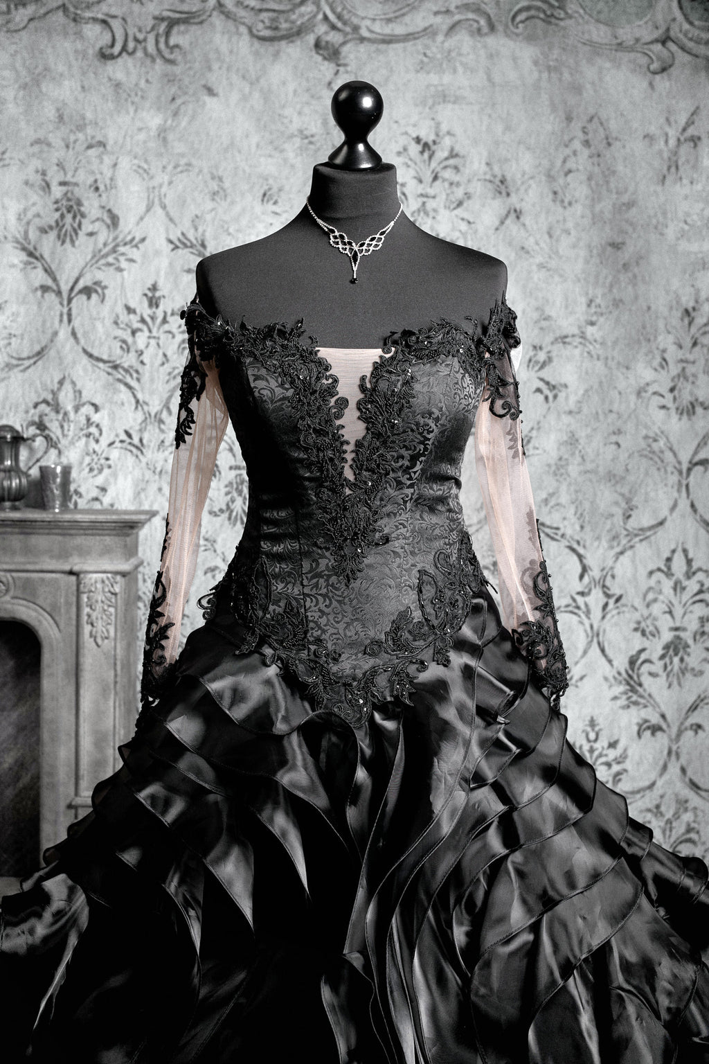 Black gothic bridal gown with sheer illusion sweetheart neckline, long sleeves with embroidered leaf lace appliqué and beaded corset bodice with floral detail