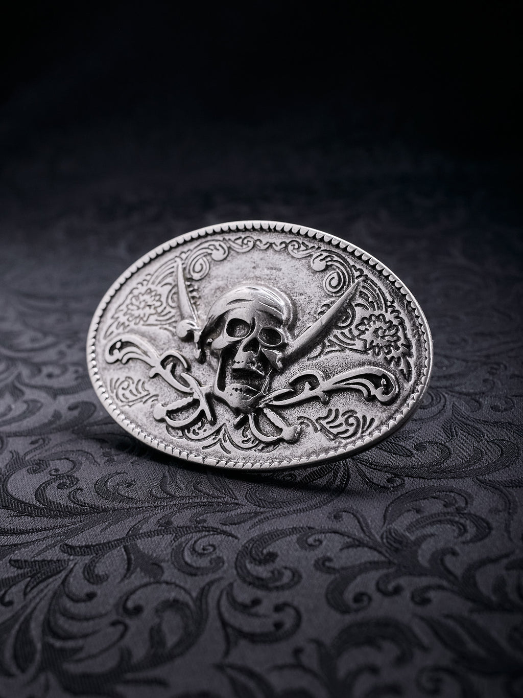 Detailed macro shot of the ornate flower patterns and the weathered silver-tone surface of the Corsair Oath buckle