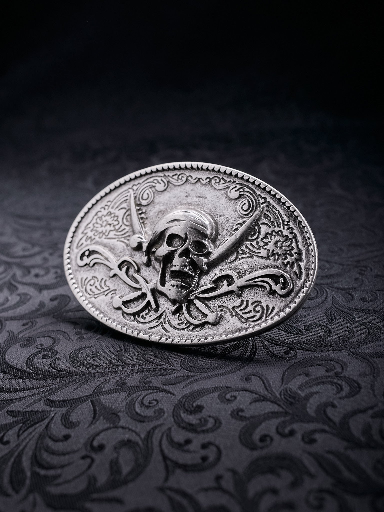 Detailed macro shot of the ornate flower patterns and the weathered silver-tone surface of the Corsair Oath buckle
