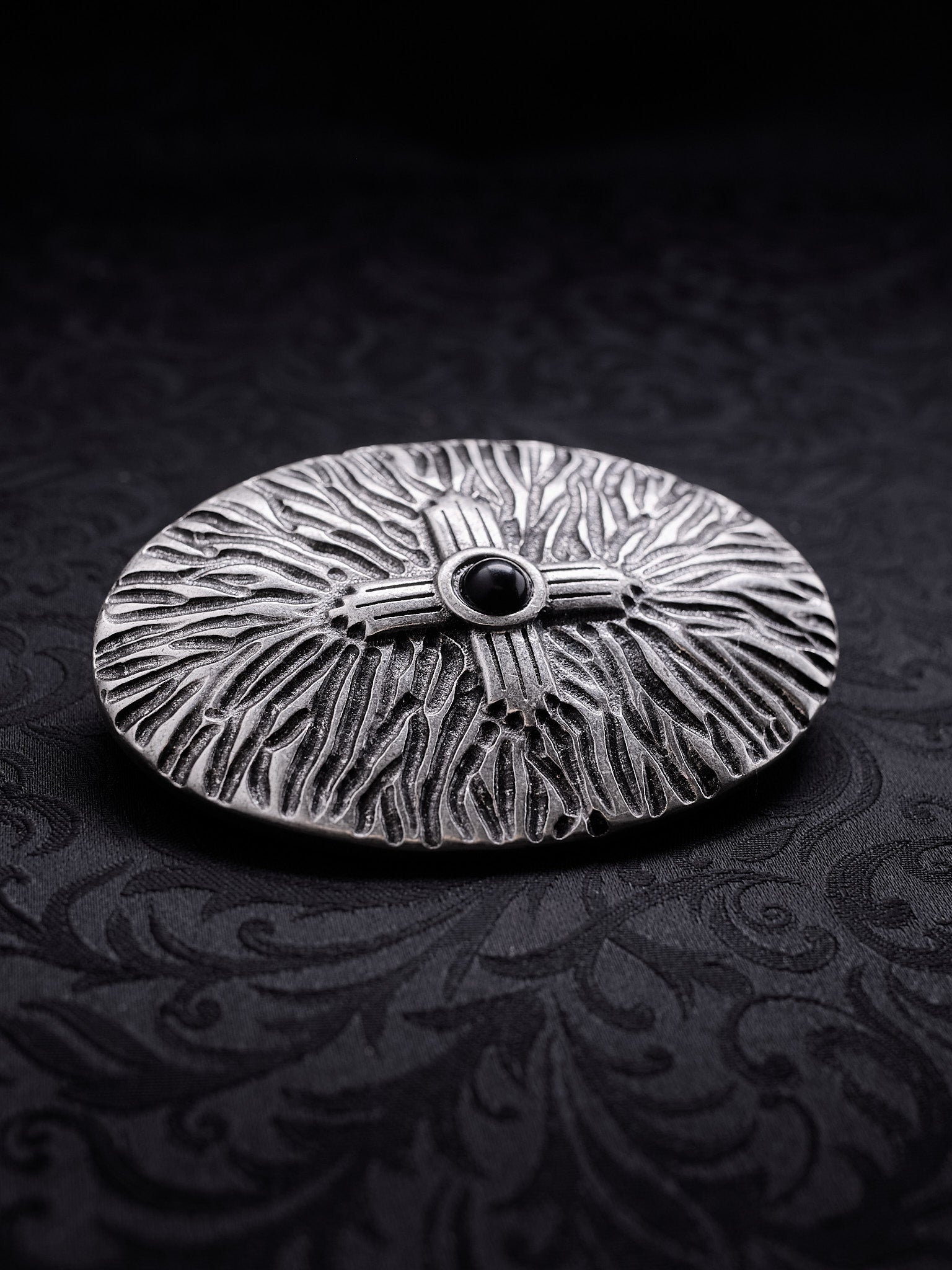 Angled view of the Black Halo metal buckle, showing the depth of the engraved patterns and the antique oxidized effect