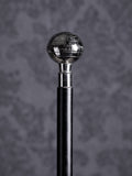 Detailed close-up of the Atlas cane handle, highlighting the engraved names of oceans and geographical lines on the silver sphere