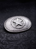Detailed close-up of the raw grainy texture and oxidized silver-tone finish on the Frontier Star belt buckle