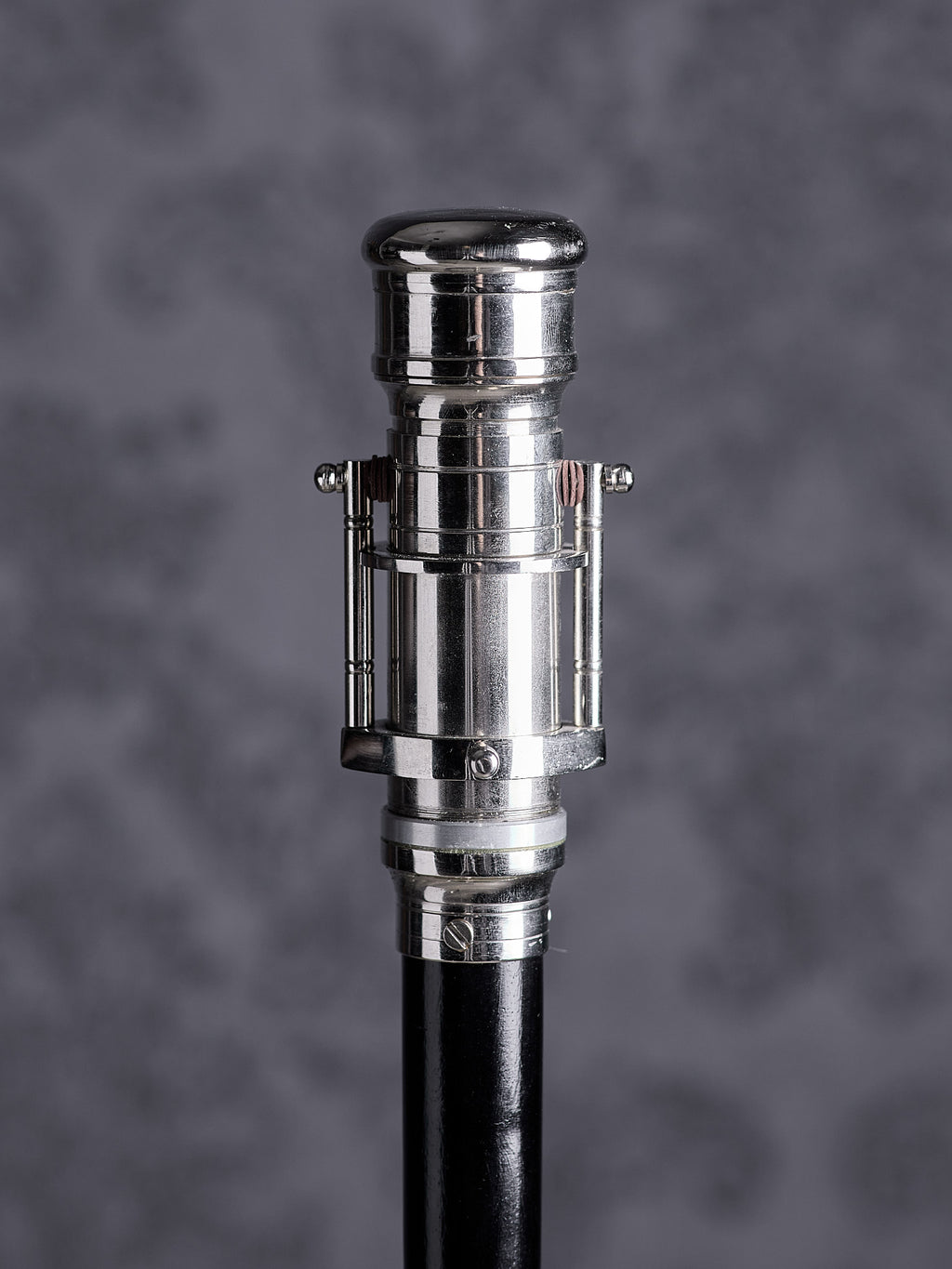 Walking cane handle designed as a decorative silver telescope on a black wooden shaft, front view