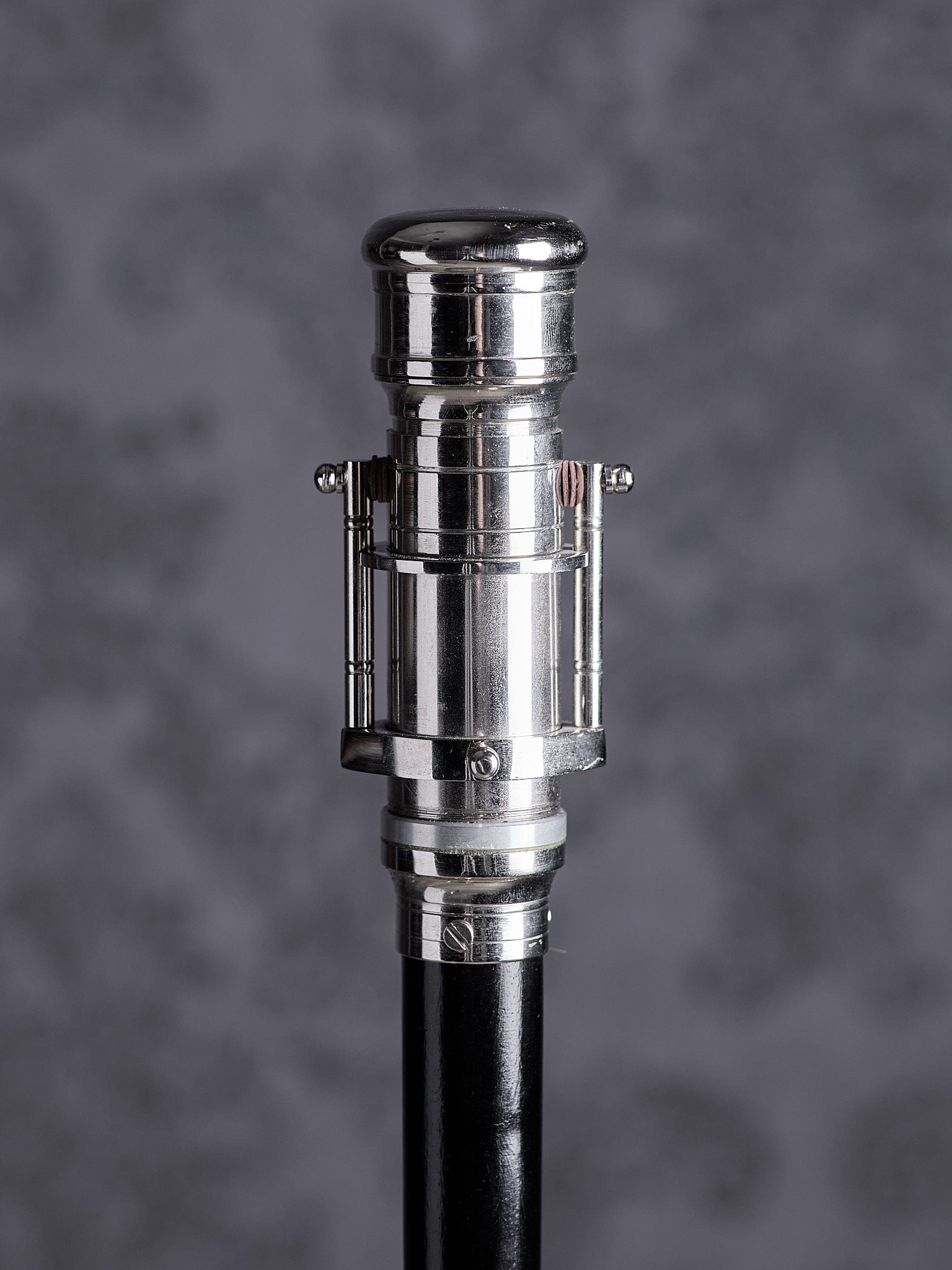 Walking cane handle designed as a decorative silver telescope on a black wooden shaft, front view
