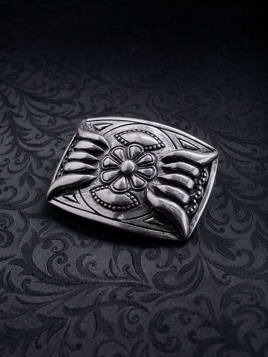 Detailed shot of the raw grainy metal texture and oxidized silver finish on the Iron Bloom belt buckle