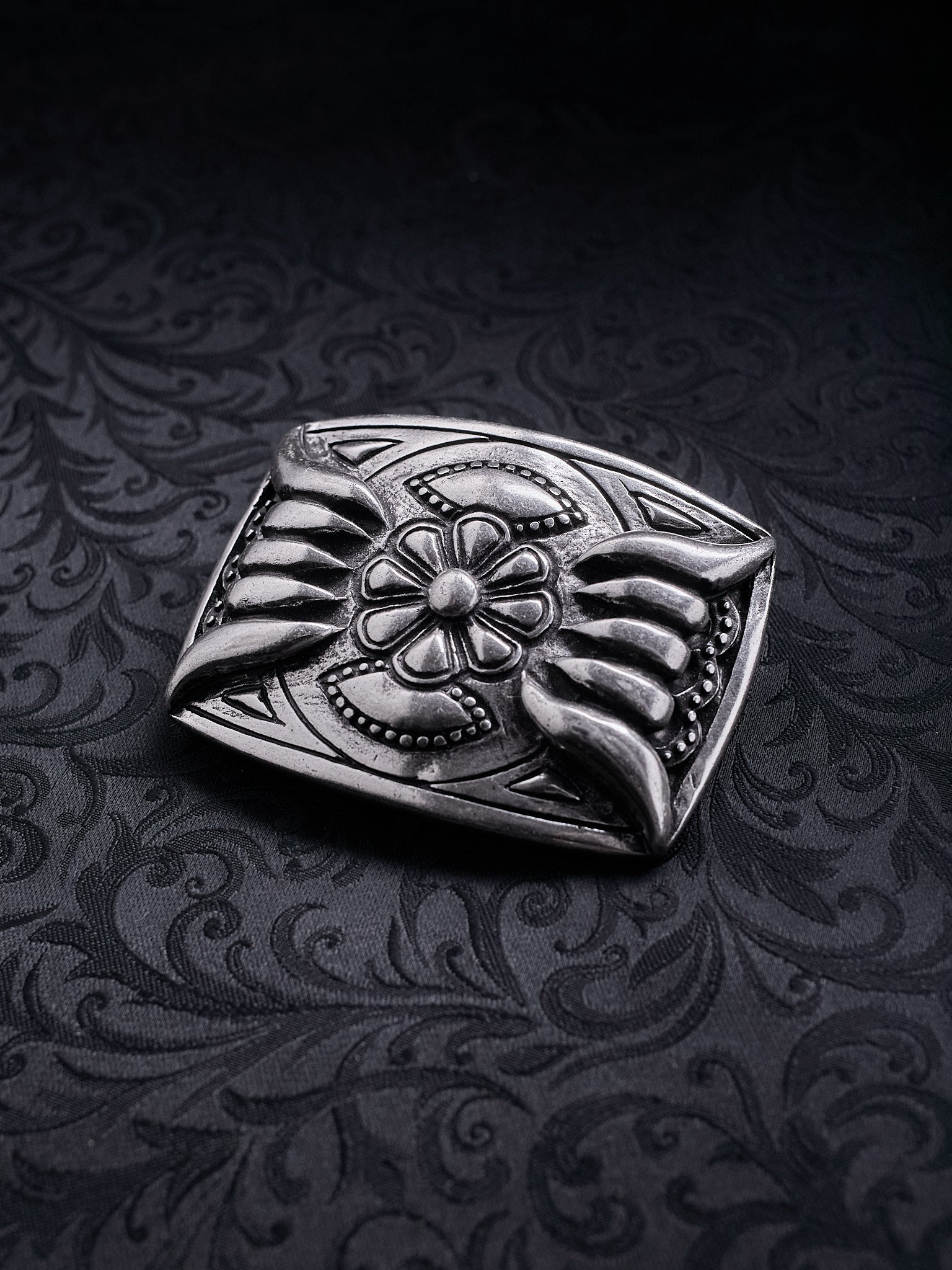 Detailed shot of the raw grainy metal texture and oxidized silver finish on the Iron Bloom belt buckle