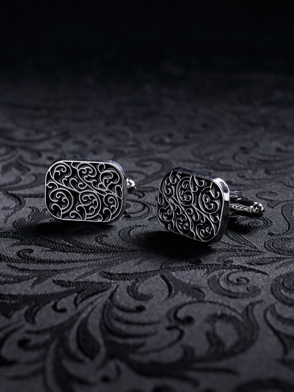 Ornamented Gothic metal cufflinks styled on a black shirt sleeve, showcasing the Victorian-inspired aesthetic for formal wear
