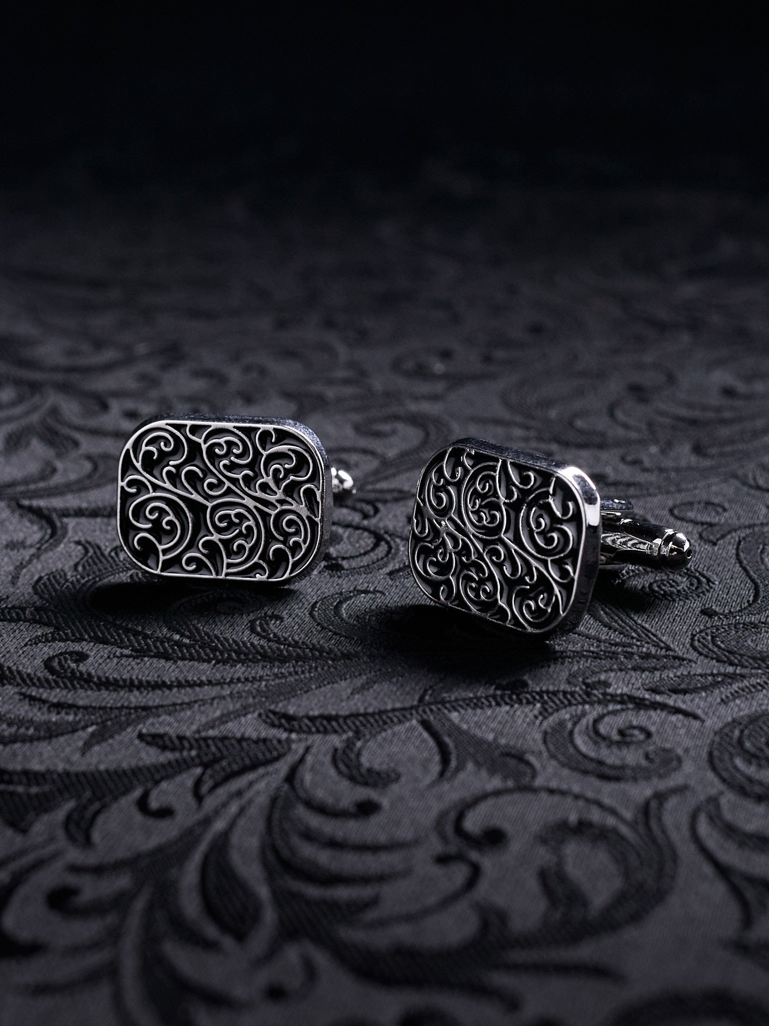Ornamented Gothic metal cufflinks styled on a black shirt sleeve, showcasing the Victorian-inspired aesthetic for formal wear