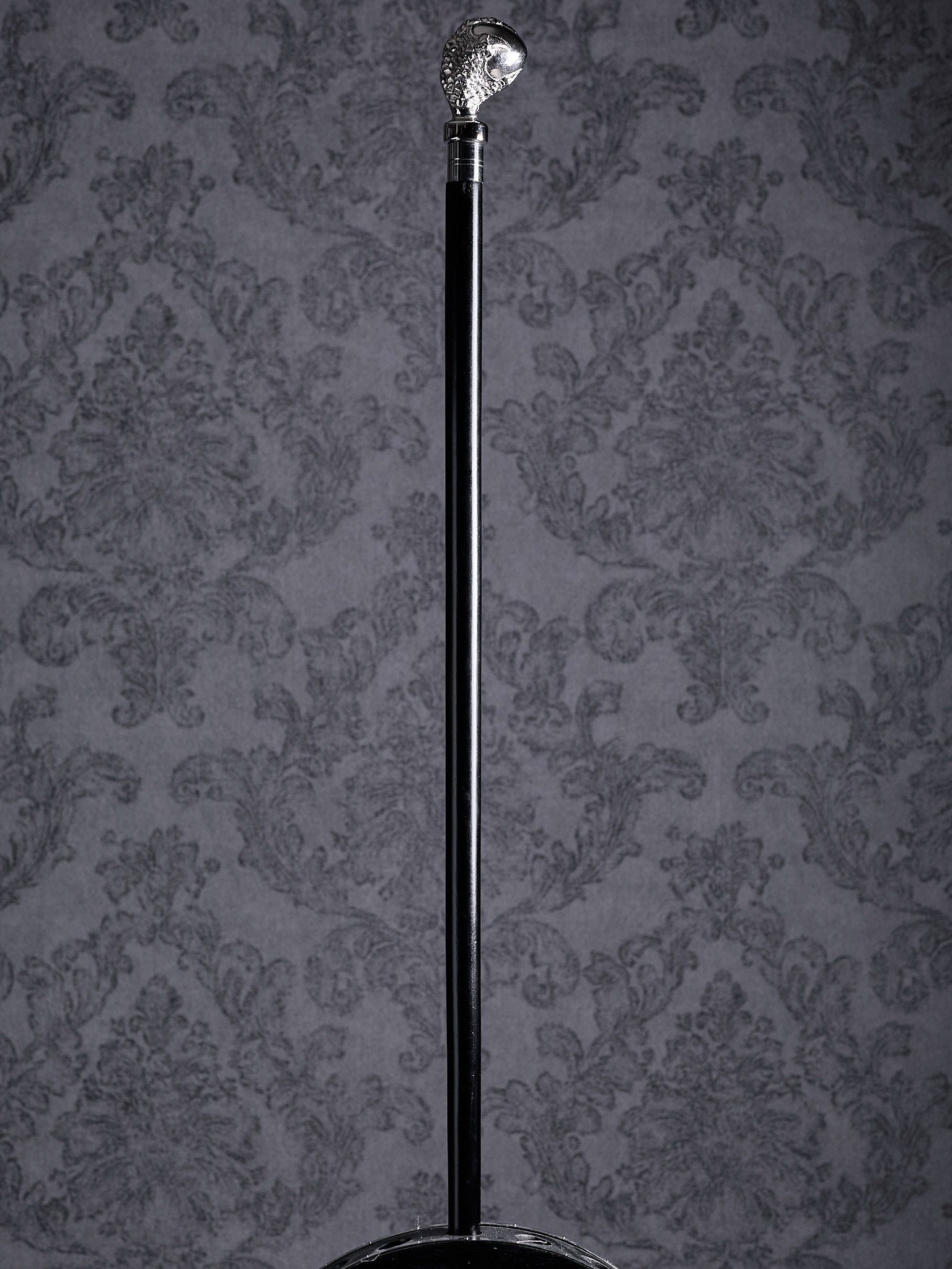 Full-length view of the Reptilian Grasp walking cane with its distinctive claw handle and sleek black shaft on a grey background