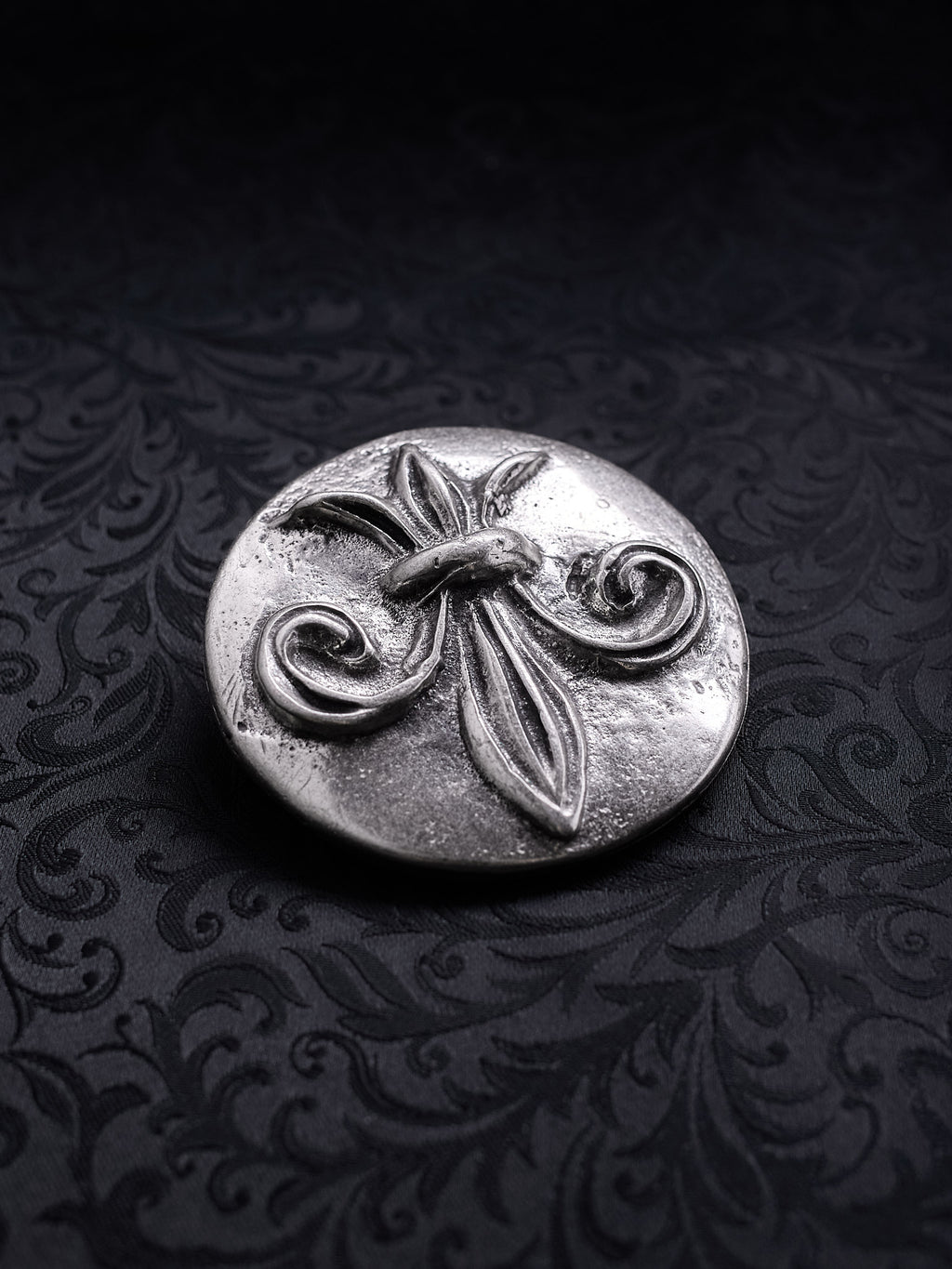 Detailed close-up of the coarse grainy metal surface and ornate scrollwork on the Sable Fleur buckle