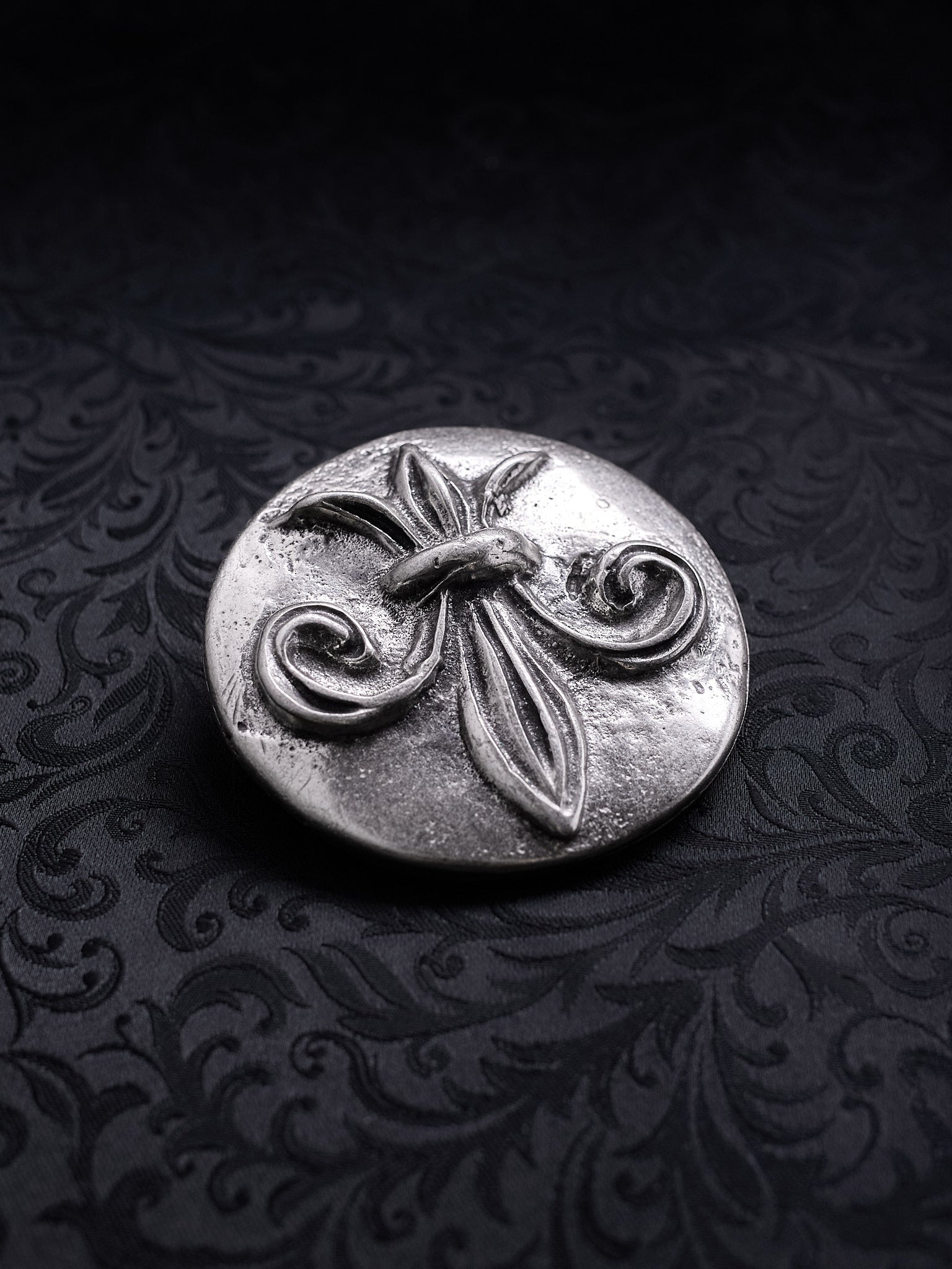 Detailed close-up of the coarse grainy metal surface and ornate scrollwork on the Sable Fleur buckle