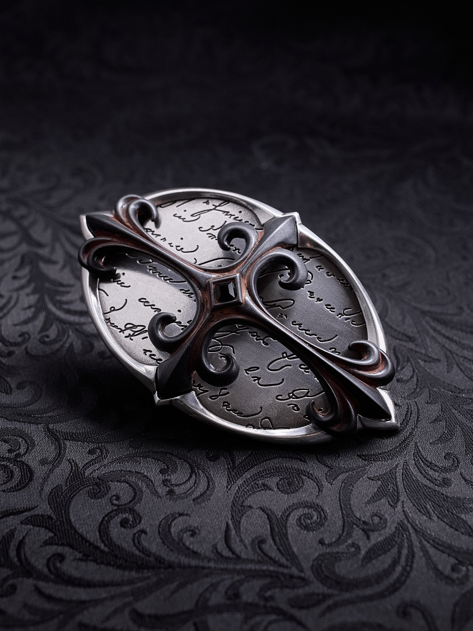 Detailed shot of the hand-written script etching and the central dark stone on the Scriptum Obscura buckle