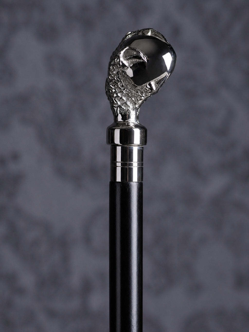 Detailed close-up of the Reptilian Grasp cane handle, highlighting the intricate scale textures on the claw and the polished finish of the orb