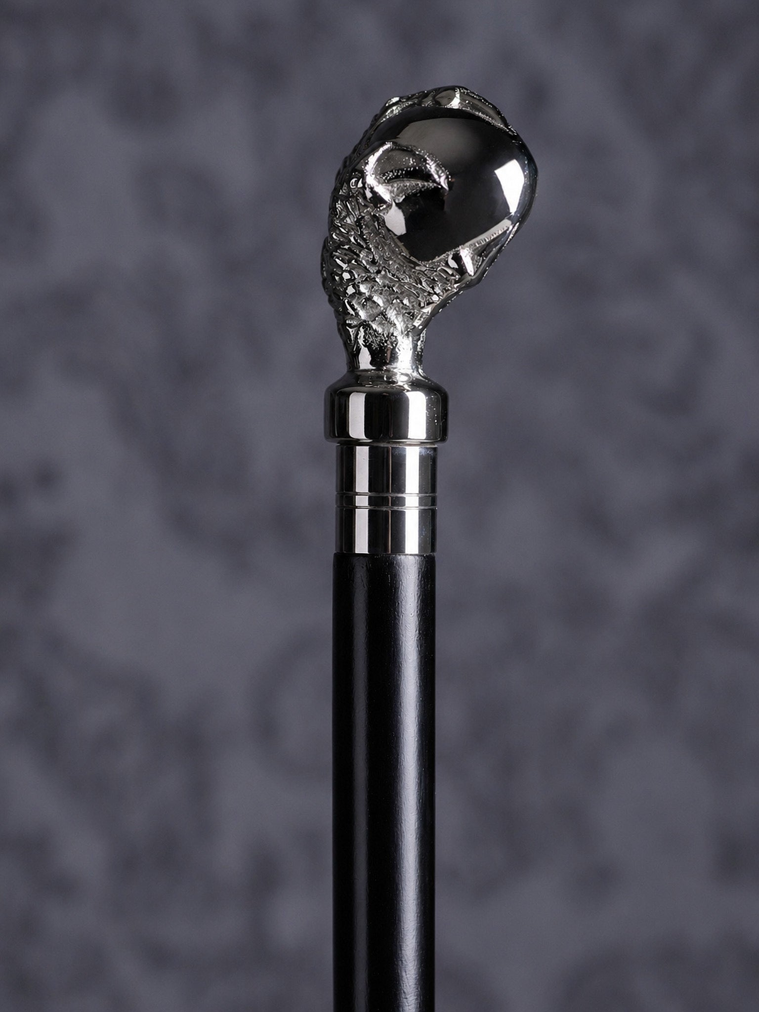 Detailed close-up of the Reptilian Grasp cane handle, highlighting the intricate scale textures on the claw and the polished finish of the orb