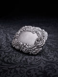 Ornate metal belt buckle named Velour Nocturne with a decorative floral baroque frame on a black background