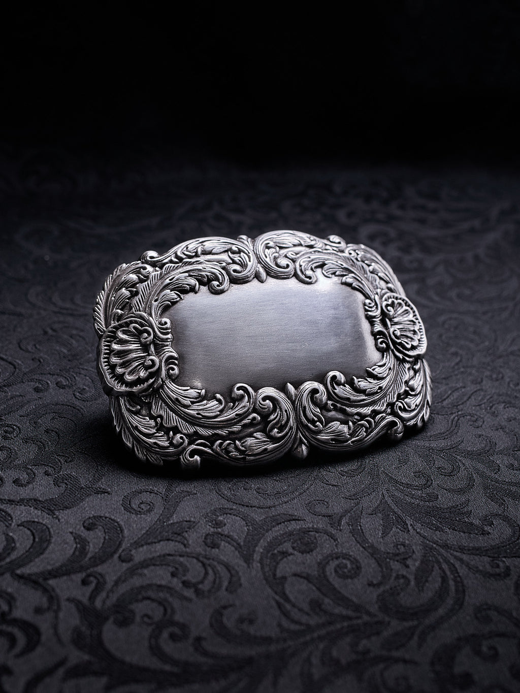 Detailed close-up of the swirling leaf motifs and oxidized silver-tone finish on the Velour Nocturne buckle