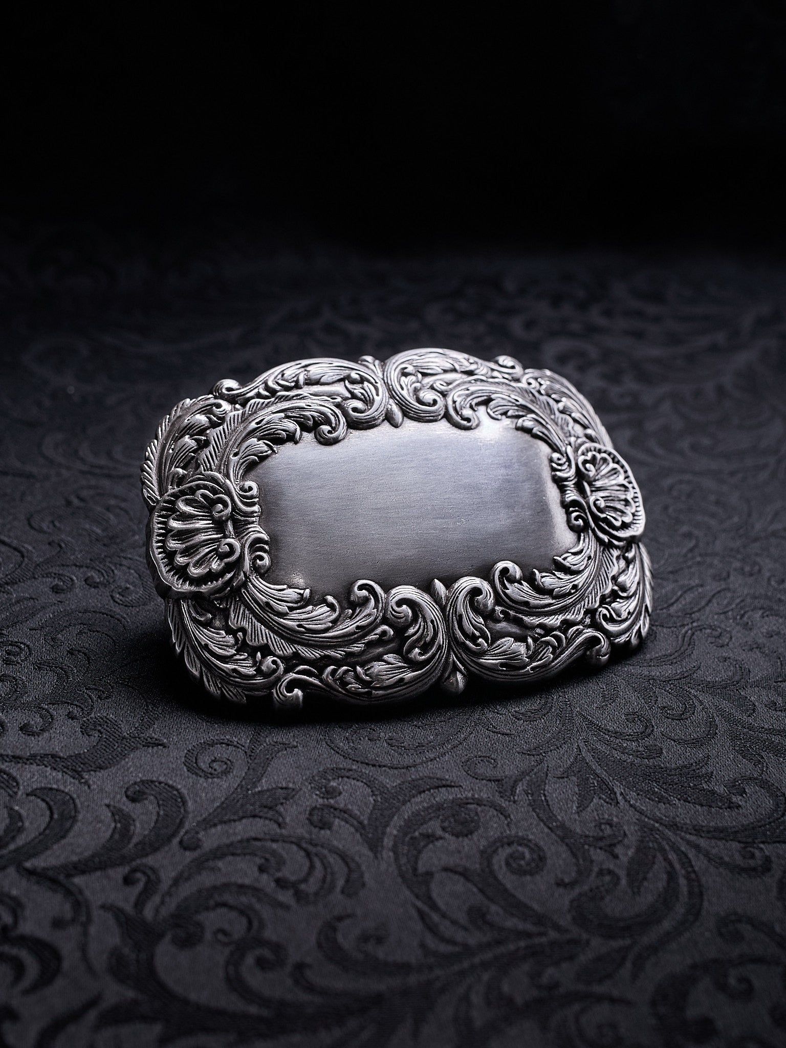 Detailed close-up of the swirling leaf motifs and oxidized silver-tone finish on the Velour Nocturne buckle